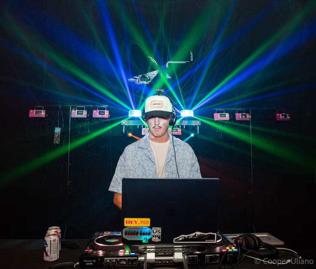 J3RD performing behind the decks under green club lasers